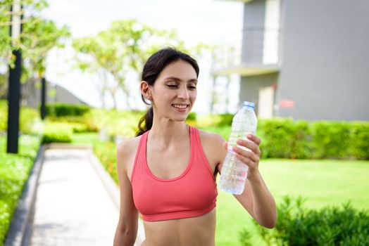 Beautiful woman runner has drinking water in the garden.