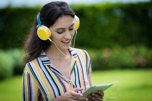 Portrait of a beautiful woman has listening to music with smiling and relax in the garden.