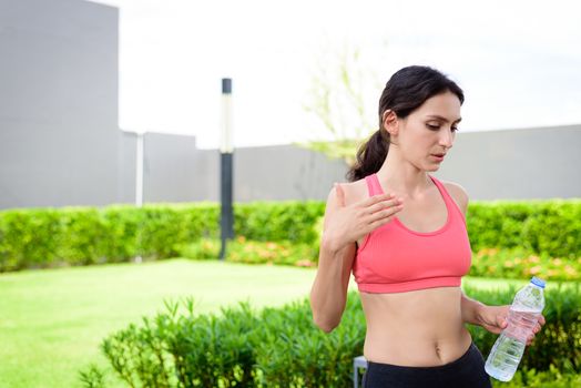 Beautiful woman runner has drinking water in the garden.