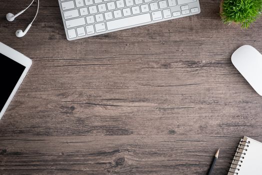 The office desk flat lay view with keyboard, mouse, tree, book, pencil and earphone on wood texture background.