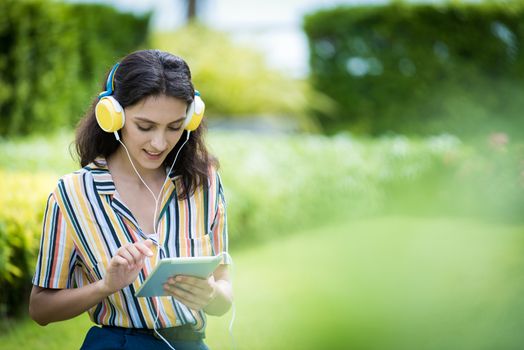 Portrait of a beautiful woman has listening to music with smiling and relax in the garden.