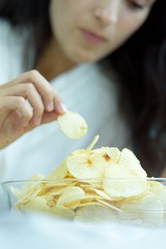 A beautiful woman eating snack potato and playing laptop with lying down on the bed and happiness at a condominium in the morning.