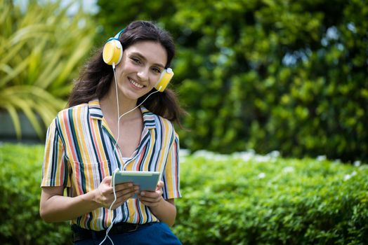 Portrait of a beautiful woman has listening to music with smiling and relax in the garden.