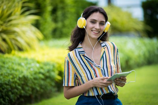 Portrait of a beautiful woman has listening to music with smiling and relax in the garden.