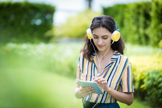 Portrait of a beautiful woman has listening to music with smiling and relax in the garden.