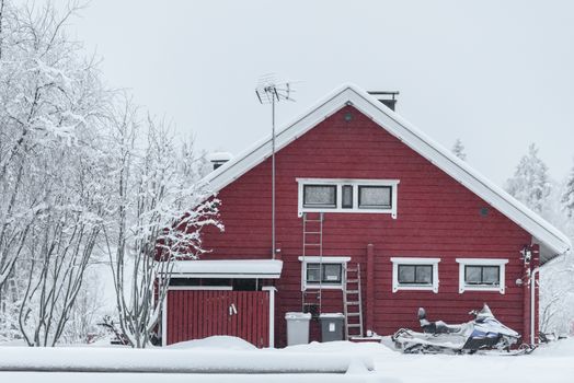 The house in the forest has covered with heavy snow and bad sky in winter season at Holiday Village Kuukiuru, Finland.