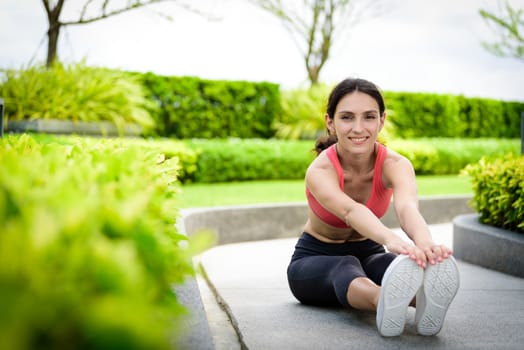 Beautiful woman runner has to warm up with stretching in the garden.