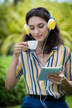 Portrait of a beautiful woman has drunk a coffee and listening to music with smiling and relax in the garden.