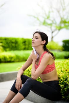 Beautiful woman runner has used a white towel wipe her face after running in the garden.