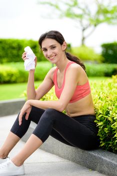 Beautiful woman runner has tired and rest for drinking water after running in the garden.