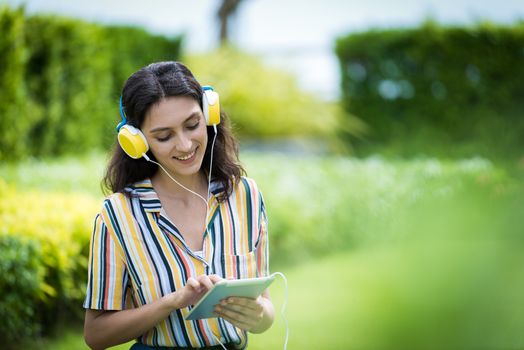 Portrait of a beautiful woman has listening to music with smiling and relax in the garden.