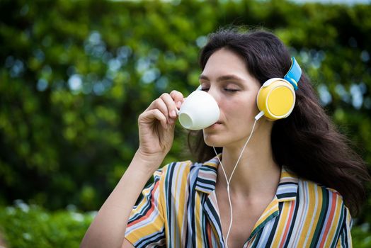 Portrait of a beautiful woman has drunk a coffee and listening to music with smiling and relax in the garden.