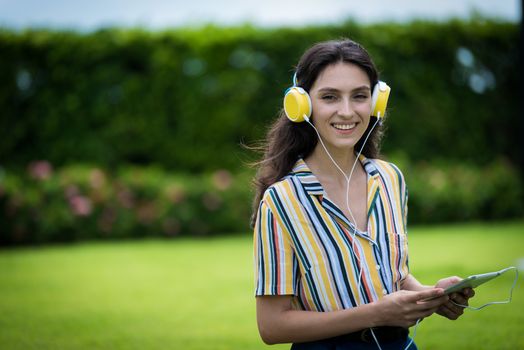 Portrait of a beautiful woman has listening to music with smiling and relax in the garden.