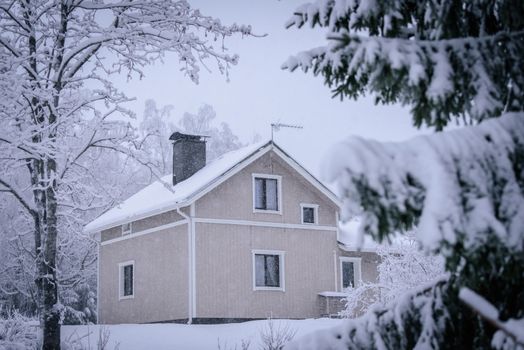 The house in the forest has covered with heavy snow and bad sky in winter season at Tuupovaara, Finland.