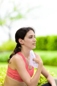 Beautiful woman runner has used a white towel wipe her face after running in the garden.