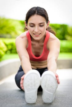 Beautiful woman runner has to warm up with stretching in the garden.