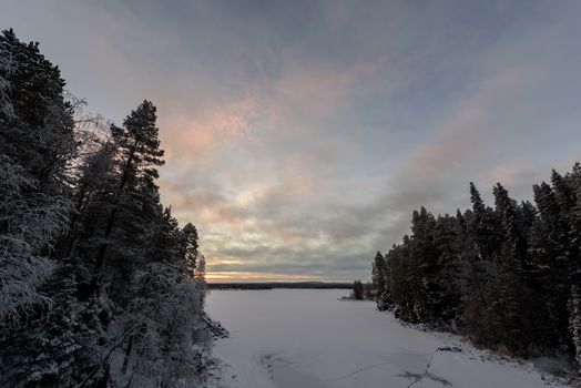 The ice lake has covered with heavy snow and sky in winter season at Oulanka National Park, Finland.
