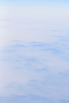 The mountains has covered by cloudy in sunrise time, view from window on the plane.