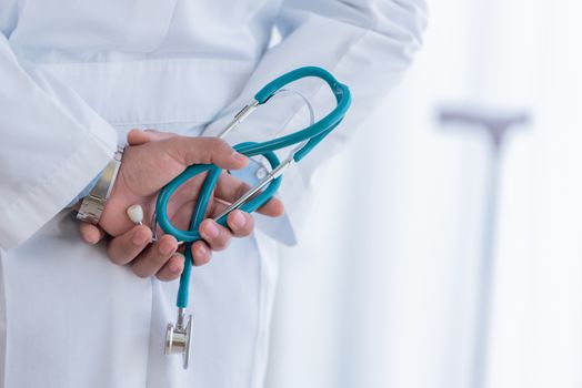 The doctor holding the stethoscope behind his back and waiting for checking the patient.