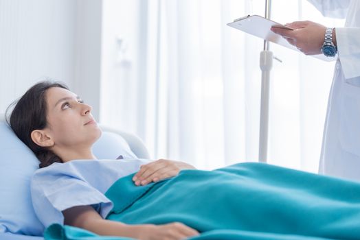 The patient woman has listening the doctor on the bed in the hospital.