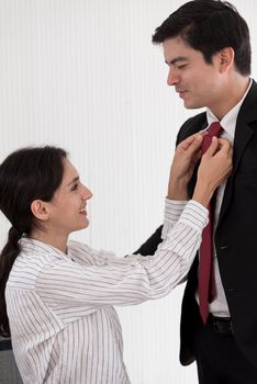 Wife tying red necktie to her husband in the office with smiling and happy.