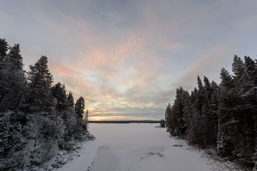 The ice lake has covered with heavy snow and sky in winter season at Oulanka National Park, Finland.