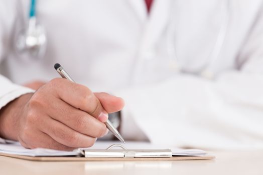 Hand of a professional doctor with silver pen over the clipboard with medical document going to make notes or prescription.