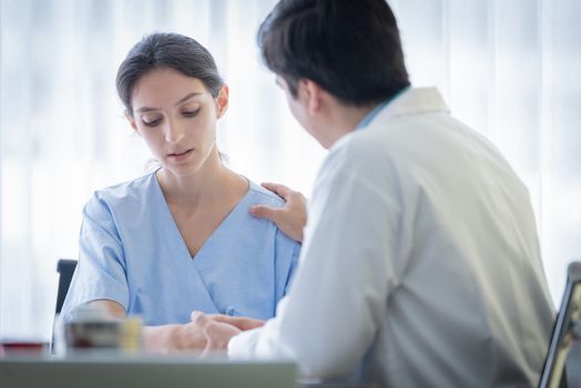 A doctor takes care of a sick patient woman with sadness and unhappiness at the hospital or medical clinic.