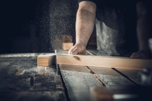carpenter cuts wooden plank on circular saw.