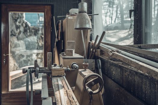 old lathe in an old carpenter's standing by a window covered with dust and spiderwebs.