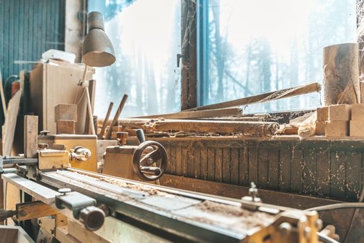 old lathe in an old carpenter's standing by a window covered with dust and spiderwebs.