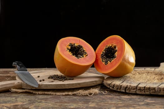 Ripe papaya fruit cut into pieces on wooden background.