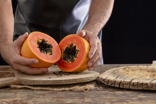 Ripe papaya fruit cut into pieces on wooden background.