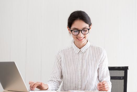 A businesswoman wearing glasses working with smiling and happiness at the office.