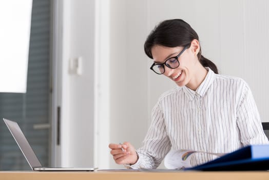 A businesswoman wearing glasses working with smiling and happiness at the office.