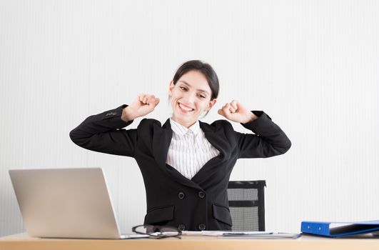 A businesswoman has taken a rest and stretching on the office chair with smiling and happiness.