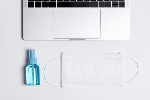 The equipment to protect COVID-19, white mask and hand cleaner gel before working in the office with laptop.
