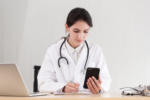A doctor woman has to work with a mobile phone at the hospital.