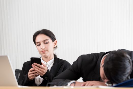 Two employees have lazy and playing the phone and sleep at the office in a relaxing time.