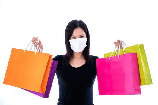 An Asian woman shopping with colorful paper bag and wearing a white mask to protect COVID-19.