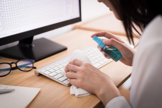 A beautiful Asian businesswoman cleaning a keyboard by cleaner gel and white cloth to protect COVID-19 before start working from home with safety and happiness.