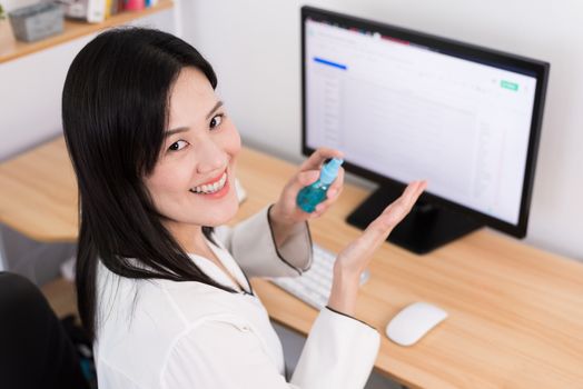 A beautiful Asian businesswoman cleaning hands by cleaner gel to protect COVID-19 before start working from home with safety and happiness.