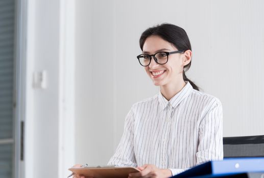 A businesswoman wearing glasses working with smiling and happiness at the office.