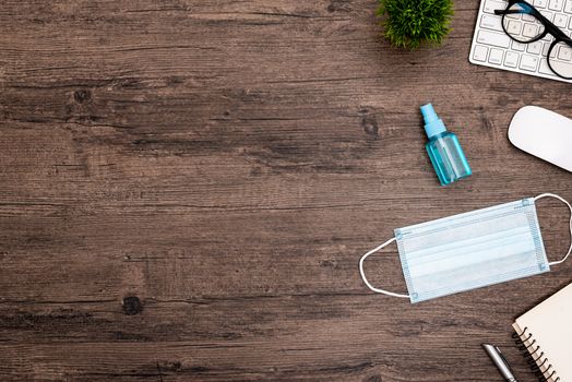The equipment to protect COVID-19, blue mask and hand cleaner gel for preparing to work from home Isolated on wood desk.