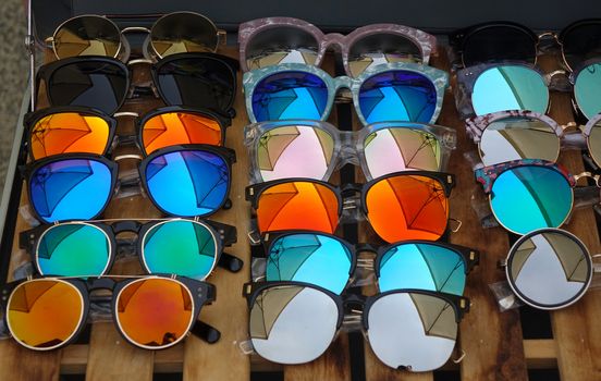 An outdoor vendor at a tourist market sells reflecting sunglasses.