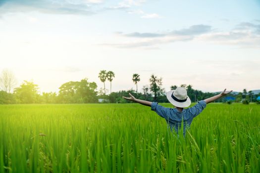 Behind the farmer woman's hands raised in the sky in a field with sky background