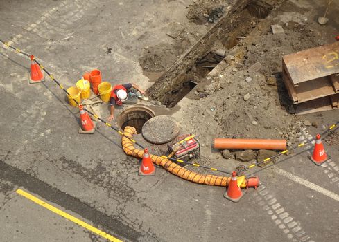 Workers lay new sewer pipes underneath a public road
