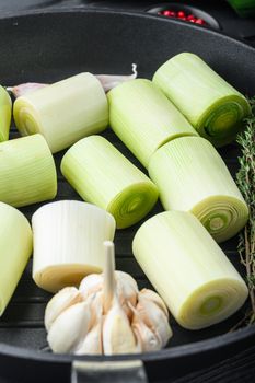 Raw braised Leek sultan on grill pan uncooked with herbs ingredients , on black wooden table side view