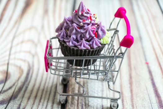 beautiful cupcake dessert sweet soap placed in a shopping cart on a wooden background. Shows hobbies and skills that people are learning in the pandemic. Shot with copyspace for text