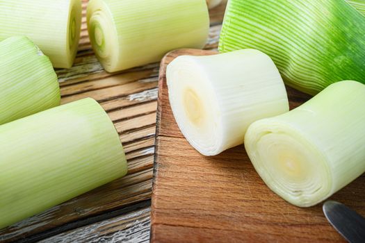 Green chopped leek sultan on choppong board over white wood table side view selective focus
